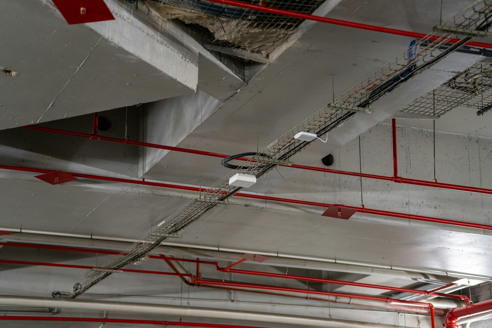 Red sprinkler pipework running across a concrete ceiling